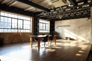 鉄骨と連窓のある棚や小物などがあるテーブルと椅子のあるフレスタの撮影スタジオ